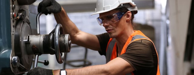 warehouse worker in ppe and safety gear working an industrial press