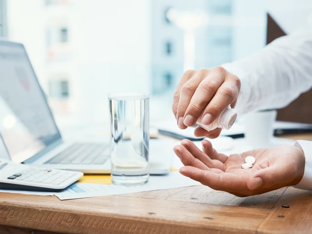 Employee taking painkillers at their desk