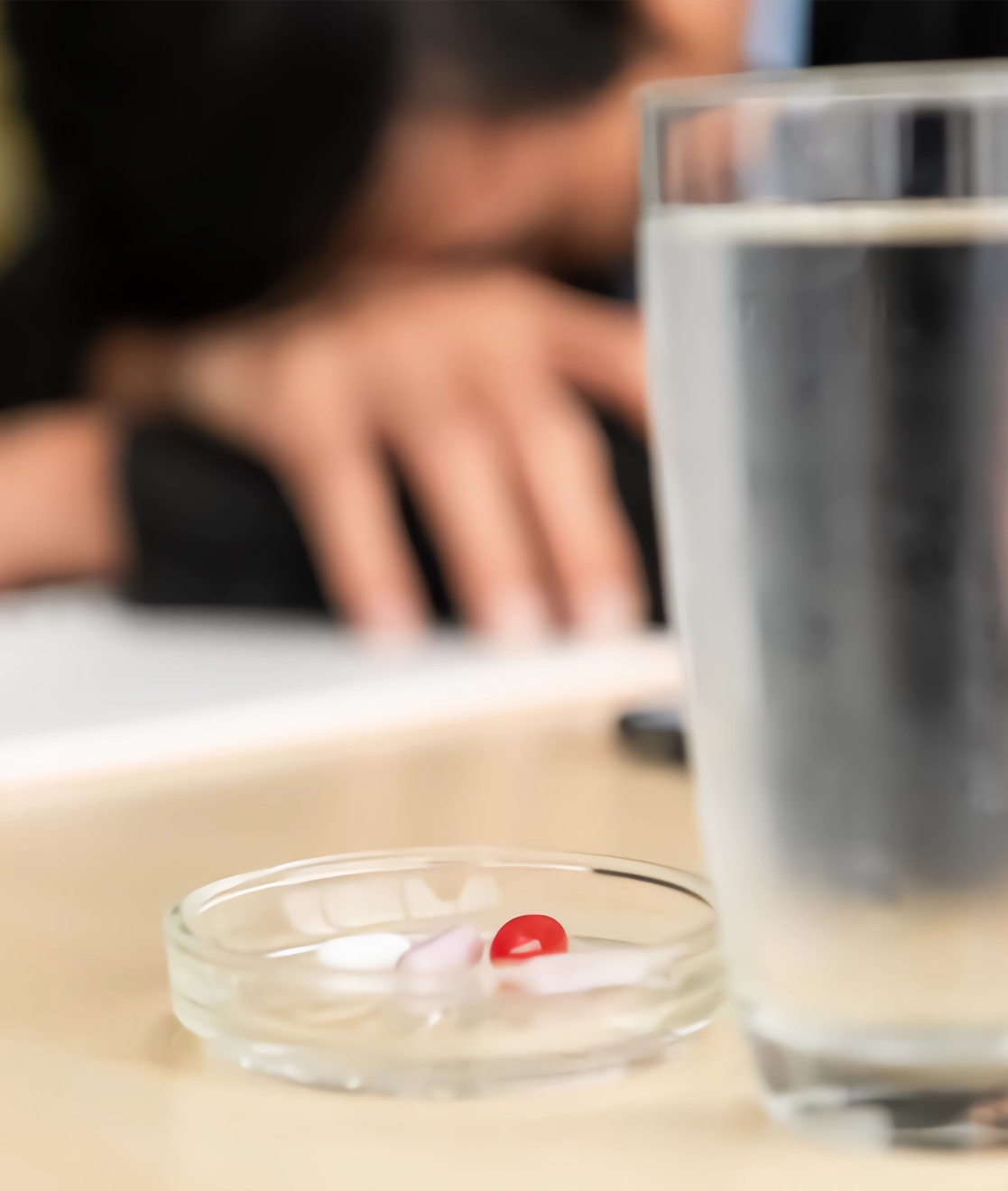 glass of water next to a dish of pills