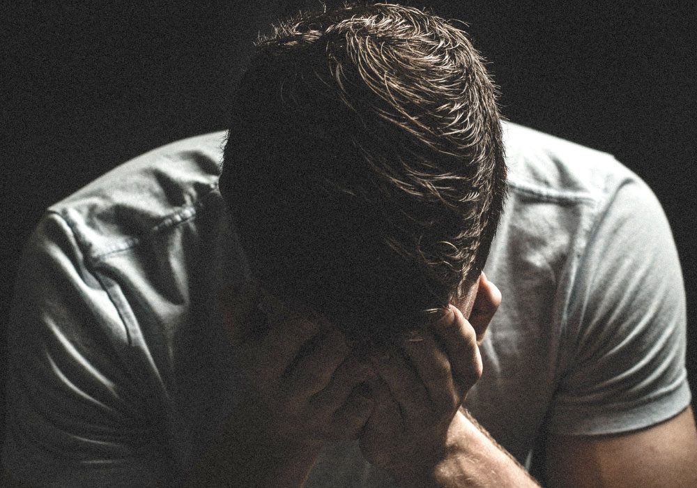 man in t-shirt with his head in his hands