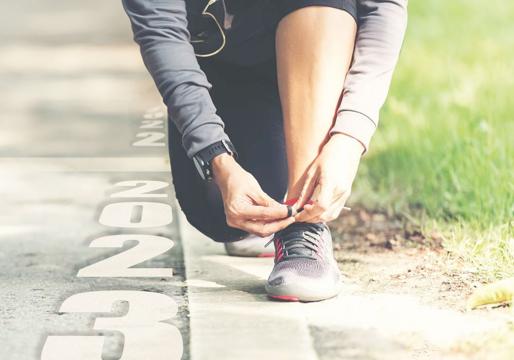 Exercising employee kneeling down to tie trainer laces