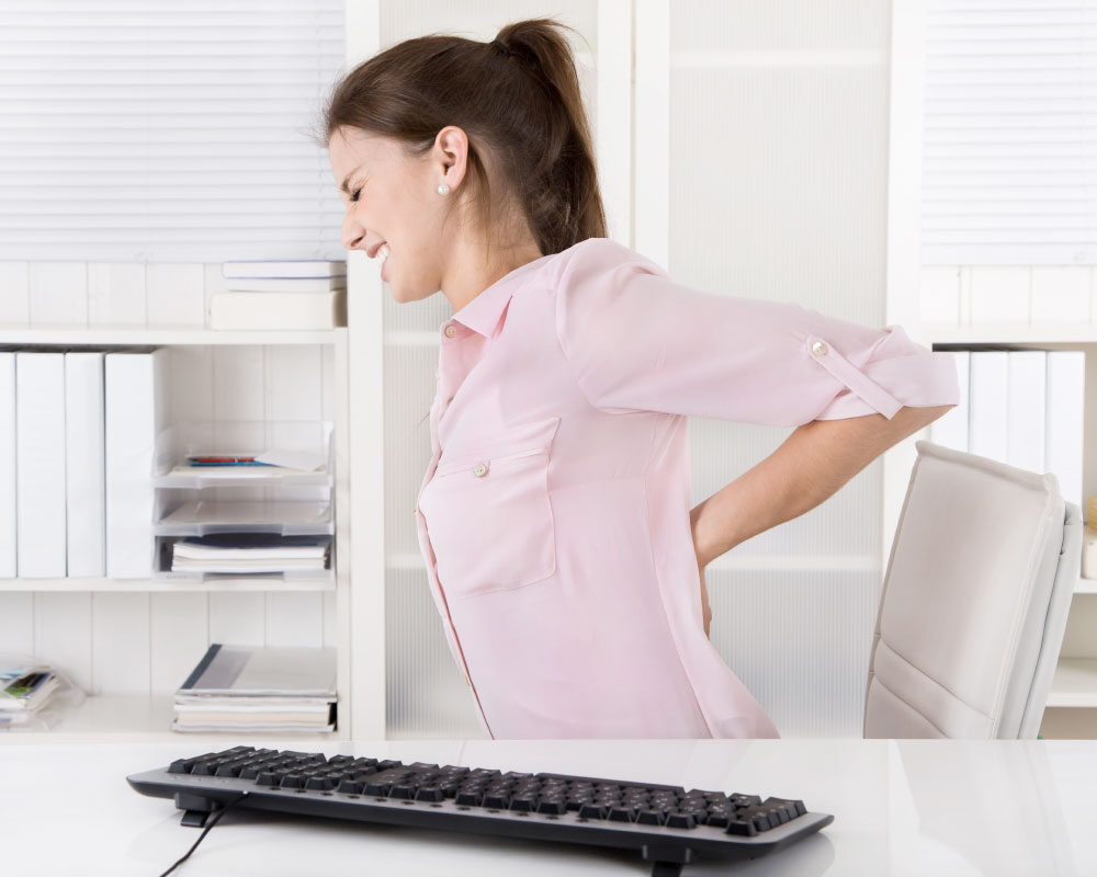 female employee at desk suffering with back pain